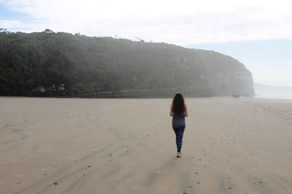 lady walking along beach at cathedral caves
