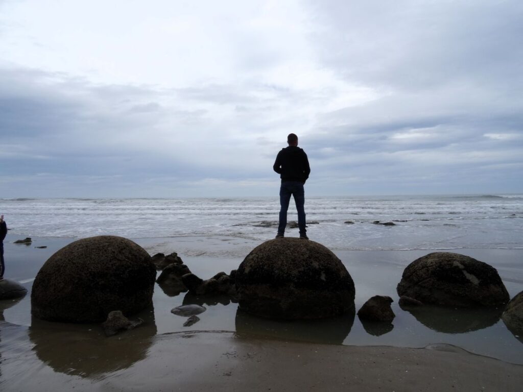 man at moeraki boulders